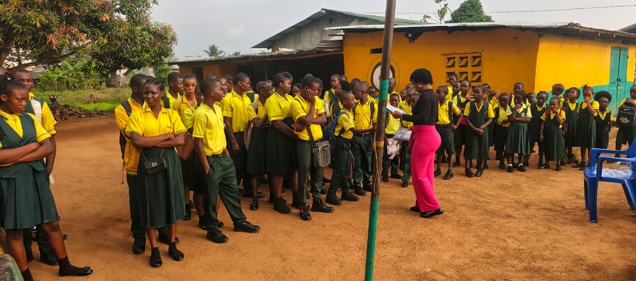 Students in school uniforms gathered outdoors for a school assembly